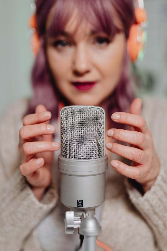 Woman with headphones recording ASMR using a microphone, focusing on sound quality.